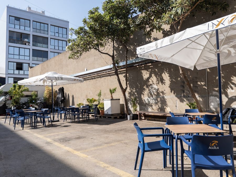 La Terraza: patio exterior con árboles, mesas y sombrillas